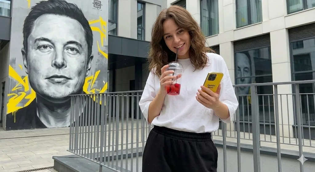 Playful girl with drink in front of musk mural — After