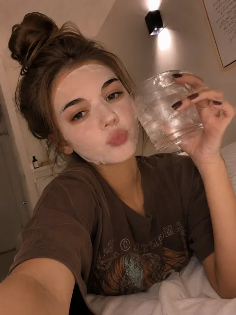Young woman skincare mask selfie tongue out