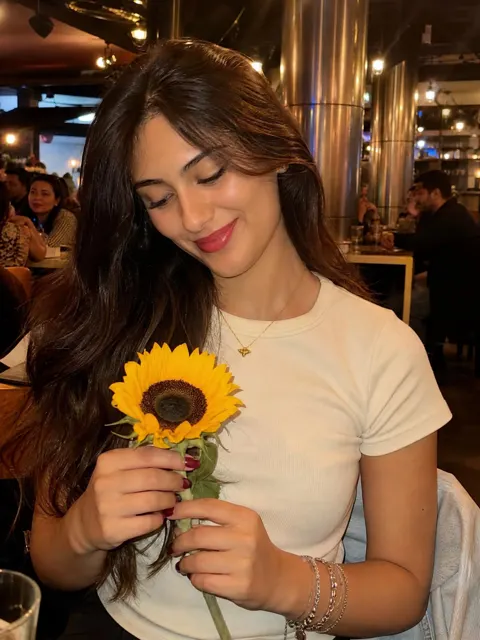 Young woman holding sunflower in warm lit restaurant
